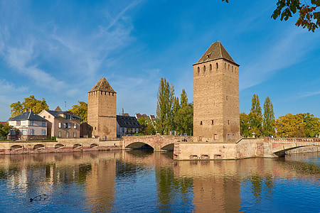 two brown brick buildings near body of water thumbnail