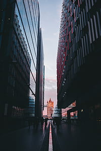 photo of people walking between two black buildings thumbnail