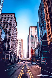 cars of road between high rise buildings thumbnail