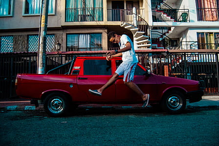 man jumps near red crew cab pickup truck thumbnail