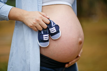 pregnant woman holding baby shoes thumbnail