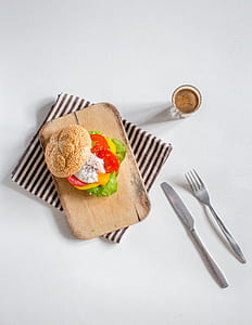 sandwich on brown wooden chopping board beside fork and bread knife thumbnail