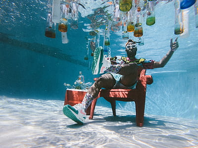 man sitting on red armchair under water thumbnail