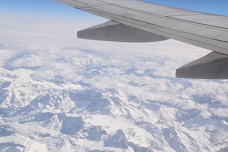 passenger plane flying over snow covered mountains thumbnail