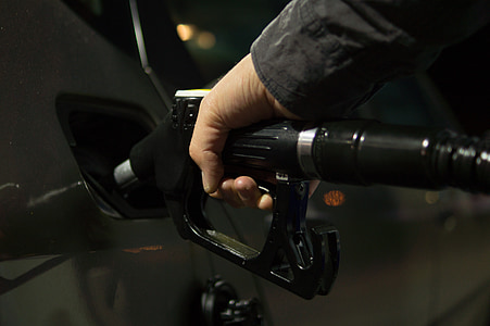 person holding black fuel nozzle mounted on car fuel tank thumbnail
