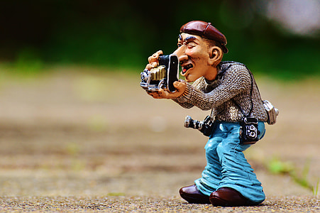 man using folding camera ceramic figurine photo thumbnail