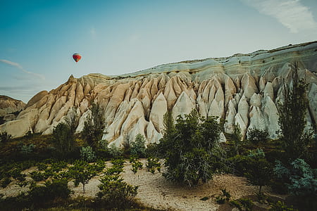 hot air balloon flying through the sky above mountains thumbnail