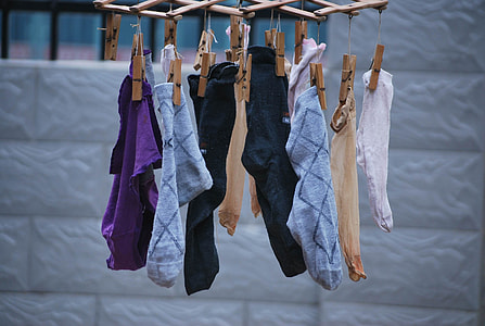 shallow focus photography of assorted socks hanging on brown wooden clothes pin thumbnail