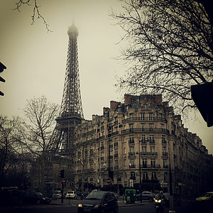 grey metal tower near a beige concrete mid-rise building with cars on road photography thumbnail