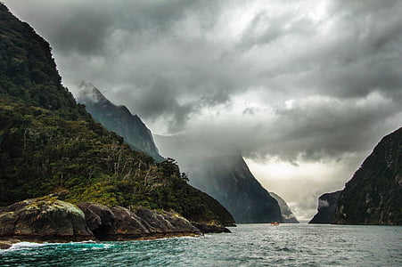 green mountains by the sea under gray clouds during daytime thumbnail
