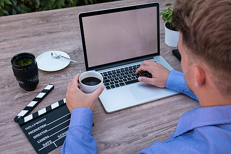man in blue dress shirt in-front of laptop computer thumbnail