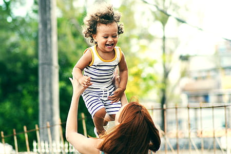 woman throwing baby in the air during raytime thumbnail