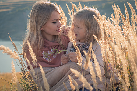 blonde haired woman and child sitting on wheat field during daytime thumbnail