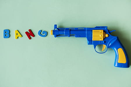 blue and yellow plastic revolver gun toy on top green surface thumbnail