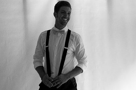 grayscale photo of man smiling standing near wall thumbnail