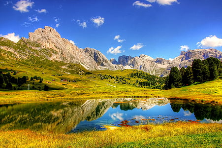 grey rock formation over body of water and green grass field thumbnail