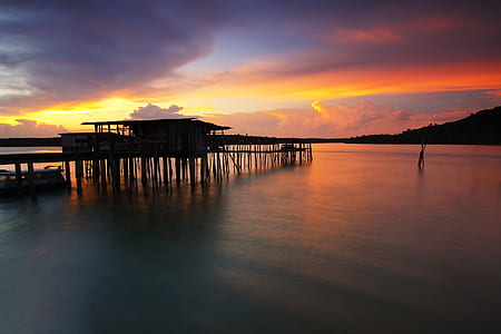Silhouette of Wooden House Above Sea during Sunset thumbnail