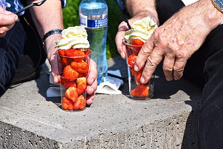 two people holding drinking glasses full of stawberries thumbnail