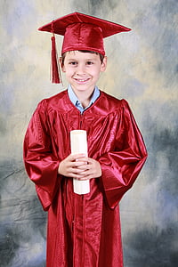 smiling boy wearing red academic dress holding diploma thumbnail
