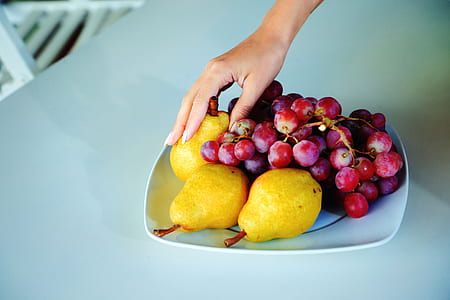 person holding pears and grapes on plate thumbnail