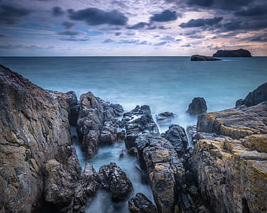 blue ocean water near rocks on shore during daytime thumbnail