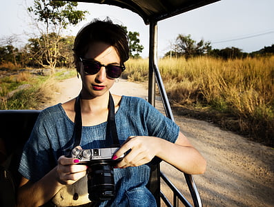 woman wearing blue top sitting on vehicle seat while holding DSLR camera thumbnail