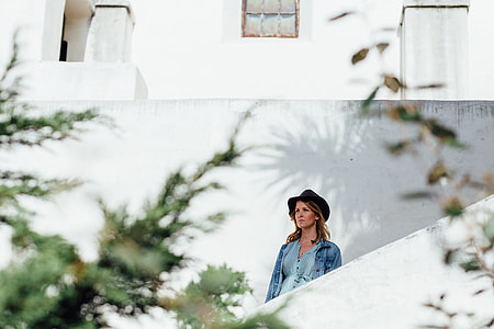 woman standing beside white wall during daytime thumbnail