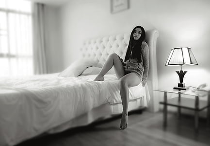 woman wearing mini dress sitting on bed near table lamp thumbnail