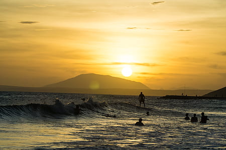 people swimming on body of water near mountain thumbnail
