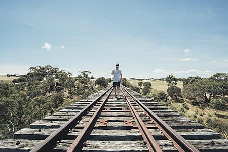 man walking on train rail at daytime thumbnail
