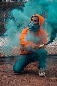 person wearing respirator mask while holding green smoke bomb thumbnail