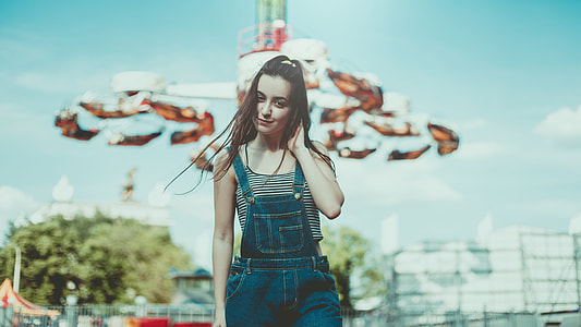 woman in blue denim jumpsuit touching her back neck thumbnail