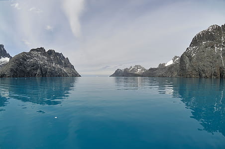 calm body of water beside rock formations thumbnail