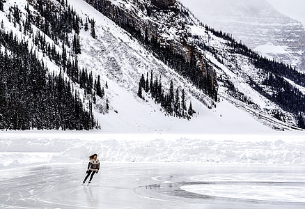 woman skating near snow-covered mountain during daytime thumbnail
