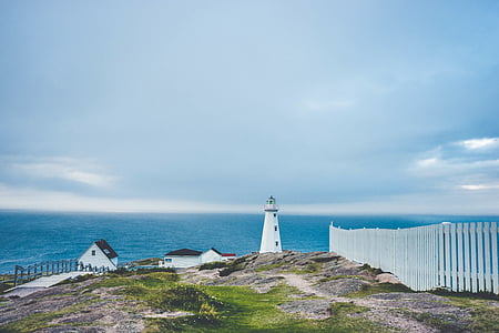 white lighthouse near wooden fence and body of water thumbnail
