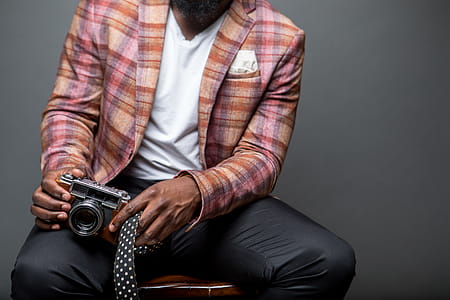 Man Holding Gray Dslr Camera Sitting on Chair thumbnail