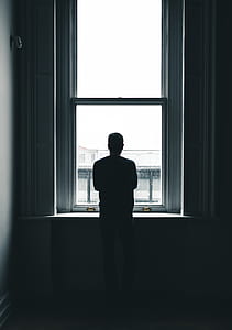 silhouette of man standing in front of window thumbnail