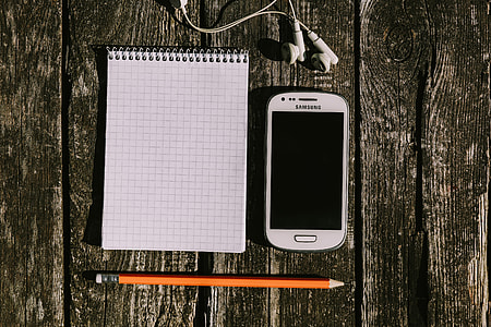White smartphone with various items on a wooden background thumbnail