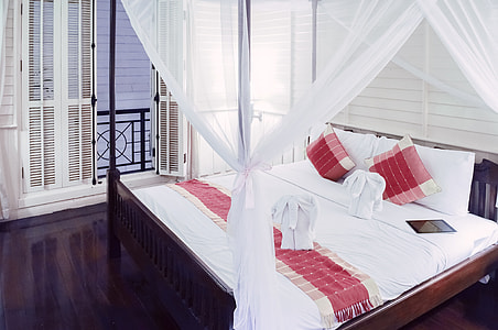 brown wooden canopy bed with white and red comforter thumbnail