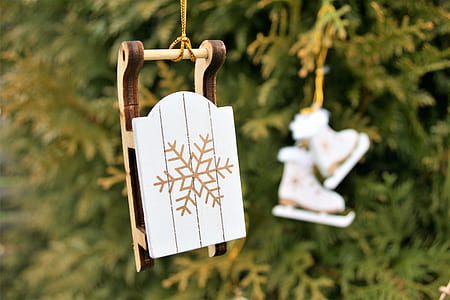 selective focus photography of white and brown snowflake-print sled decor hanging on Christmas tree thumbnail