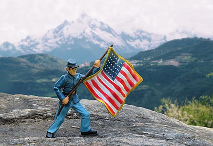 selective focus photography of soldier waving flag of America figurine thumbnail