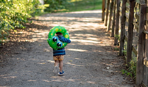 toddler carrying green inflatable floating rin thumbnail