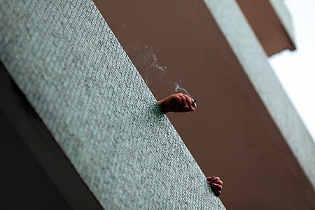 person smoking inside the gray building thumbnail