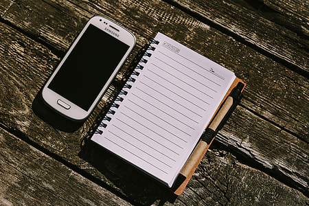 White smartphone with various items on a wooden background thumbnail