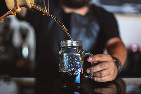 person pouring red beverage to clear glass mason mug selective focus photography thumbnail