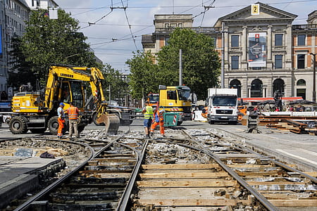 people working at the road and railroad near buildings thumbnail