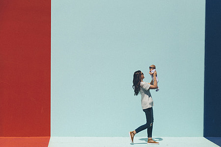 woman carrying baby beside wall thumbnail