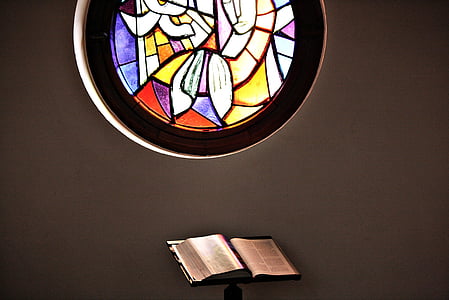 opened book near multicolored stained glass window thumbnail