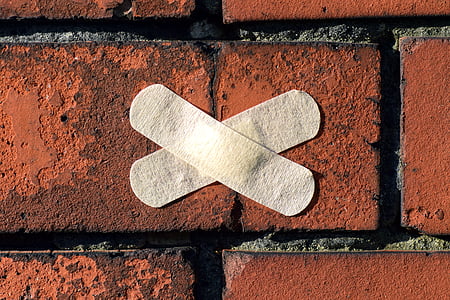 two x shaped white band aids on brown surface thumbnail