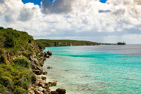 landscape photo of cliff and blue sea under white cloud blue skies thumbnail